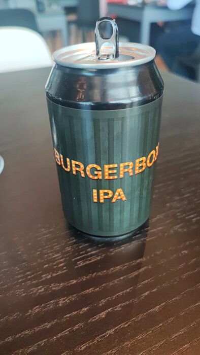 En burk Burgerbock IPA-öl står på ett bord, nyligen öppnad med kapsylen upp.