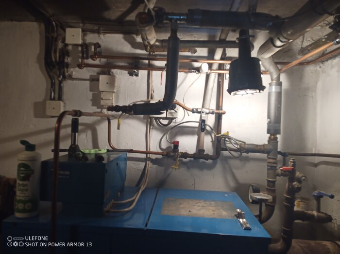 Rörledningar och installationer i ett pannrum med olika rör, ventiler och mätutrustning.