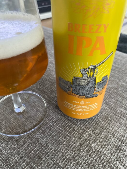 Ett glas med Breezy IPA öl och flaskan på ett bord, lämpligt för en varm sommardag.