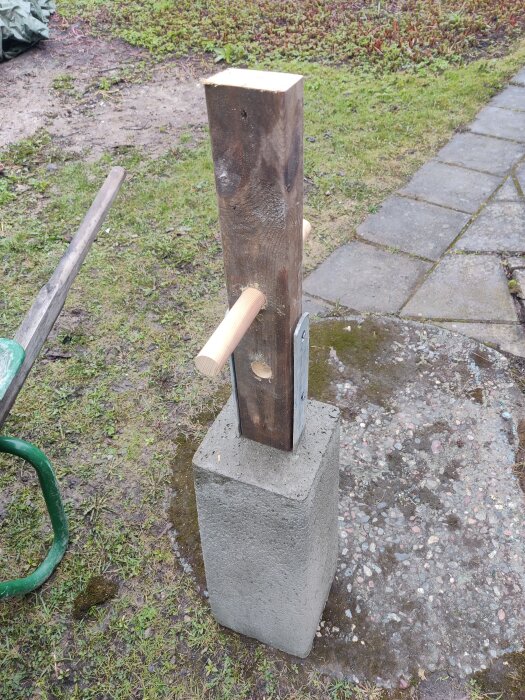 Hemgjord stöt bestående av en träbit som står på en betongpelare med en hammare vid sidan.