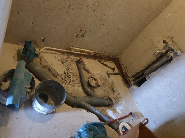 Renoveringsarbete i ett badrum med nytt avloppsrör och förseglat gammalt gjutjärnsavlopp.