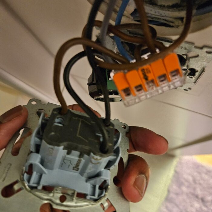 Närbild på en öppen elektrisk kopplingsdosa med flera trådar och anslutningsklemmar, sedd ovanifrån.