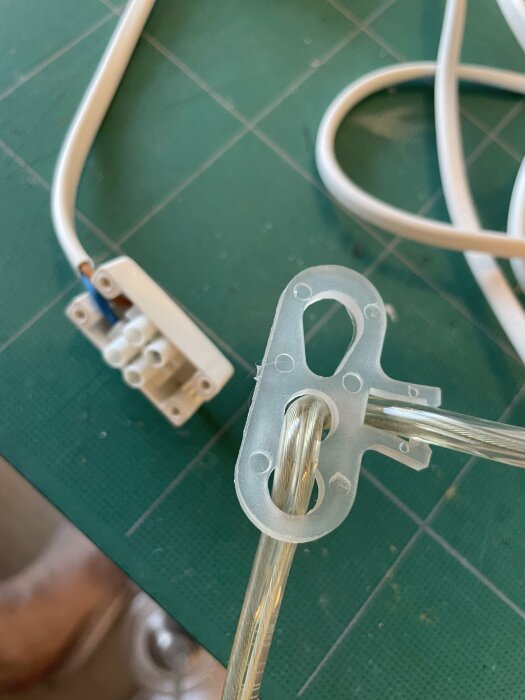 En upphängningsanordning med en kabel och en sockerbit i bakgrunden på ett grönt underlag.