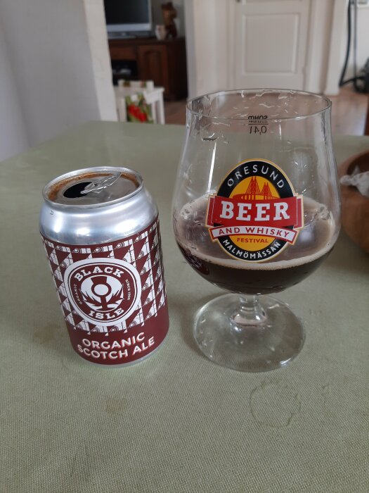 Öppnad burk av Black Isle Organic Scotch Ale bredvid ett ölglas på bord.