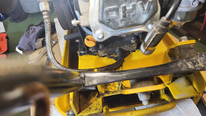 Närbild på en markvibrator med oljeläckage vid motorn på en gul maskinram.