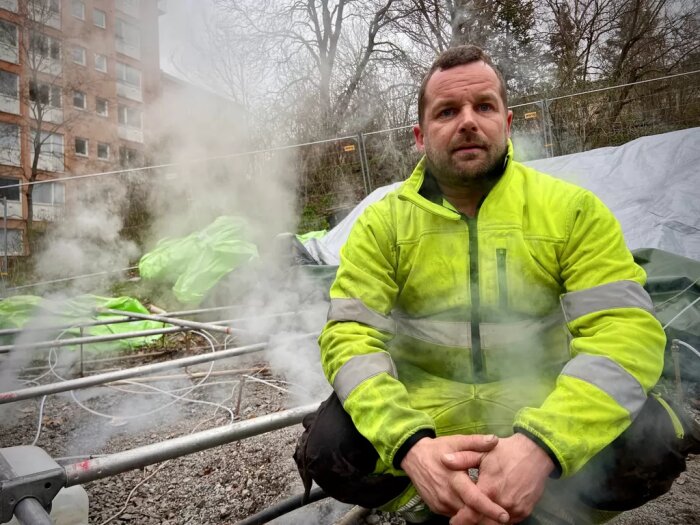 Man i arbetskläder framför ångande växtmaterial på byggplats.