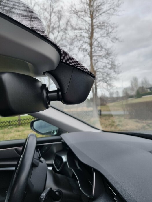 Dashcam installerad ovanför bilens instrumentbräda med utsikt genom vindrutan.