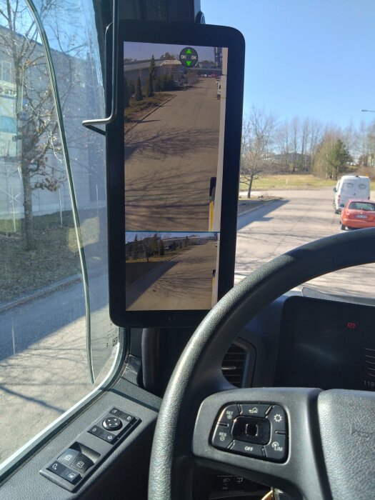 Digital bakåtspegel visar en gatuvy på en skärm monterad i ett fordon.