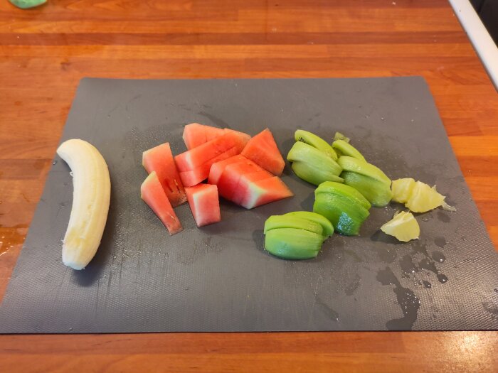 Banan, vattenmelon och kiwi uppdelade på en skärbräda som bildar en rebus.