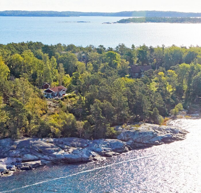 Flygbild över en ö med två sommarstugor omgivna av skog nära vattnet i Smådalarö.