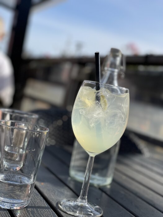 Ett glas Limoncello spritz med is och sugrör på ett soligt uteserveringsbord.