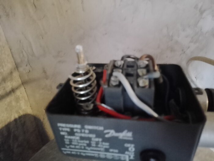 Öppen hydrofor med synliga elektriska anslutningar och justerbar fjäderspänning.