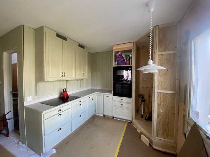 Kök under renovering med ny bänkskiva och pågående bygge av skafferi samt dörrkarm.