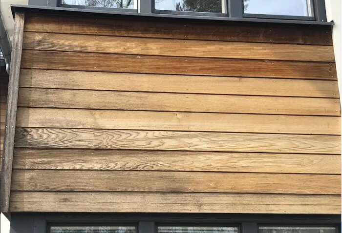 Träbeklädnad på en husvägg med varierande nyanser av brunt, horisontellt monterade plank.