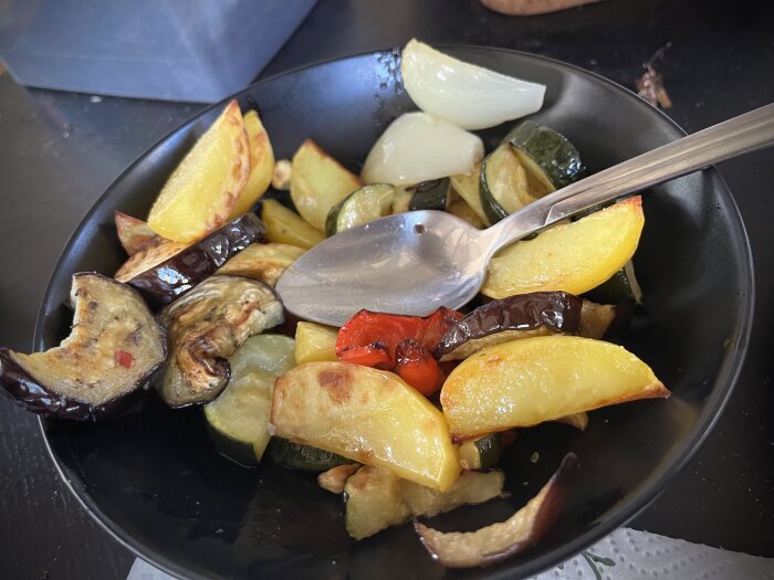 Ugnsrostade grönsaker i en skål inklusive aubergine, squash, paprika, lök och potatis.
