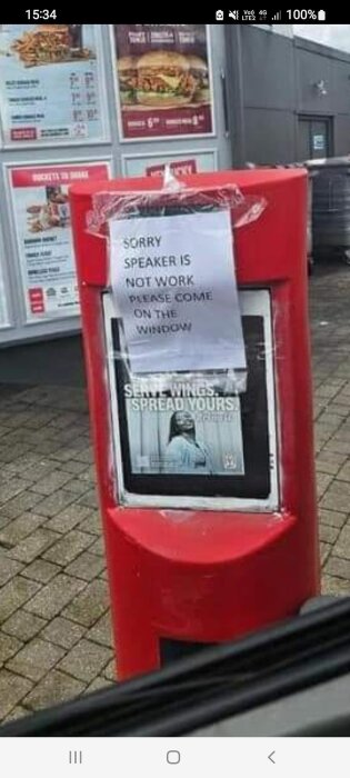 Röd drive-through beställningsterminal med skylt: "Sorry speaker is not work please come on the window".