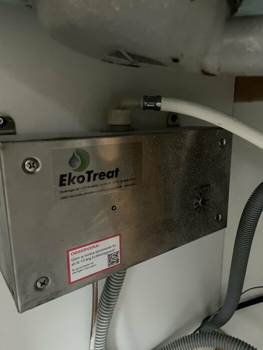 Doserpumpen under diskbänken märkt "EkoTreat" med slitage och potentiella läckagespår.
