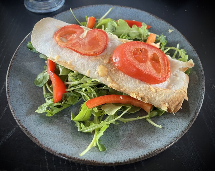 Klassisk burrito med kyckling, ost, salsasås och tomat på en bädd av salladsblad och paprika.
