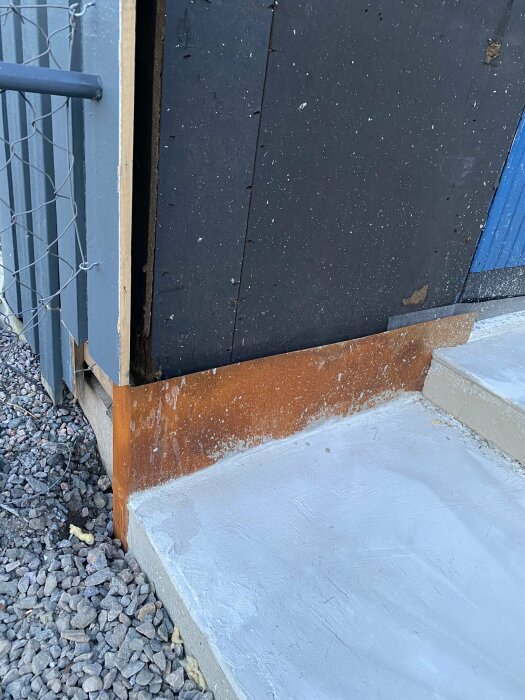 Nyutgjuten betongyta bredvid stegform där formarna har tagits bort, med synliga skador efter regn.