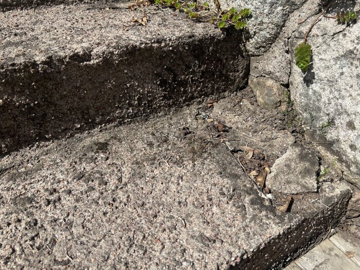 Slitet betongtrappsteg med sprickor och löst grus mot en bakgrund av berg och vegetation.