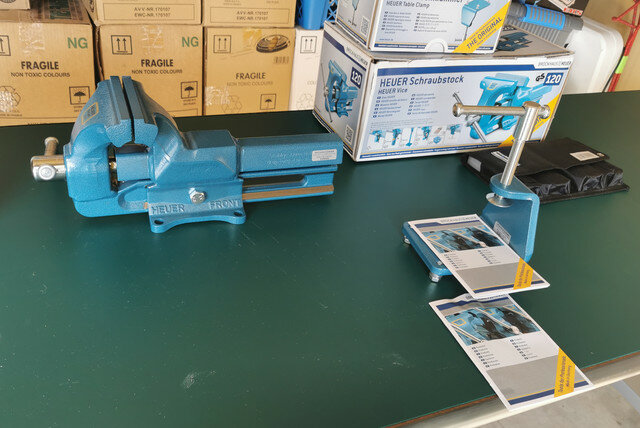 Nyuppackad Brockhaus Heuer skruvstycke i blått med tillbehör och manualer på ett arbetsbord.