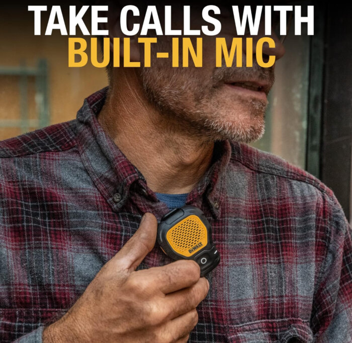 Person i rutig skjorta håller en bärbar högtalare med inbyggd mikrofon.