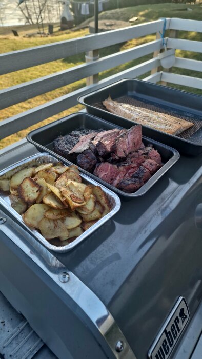 Grillad texasbiff, lax och råstekt potatis på en kol- och gasolgrill utomhus.