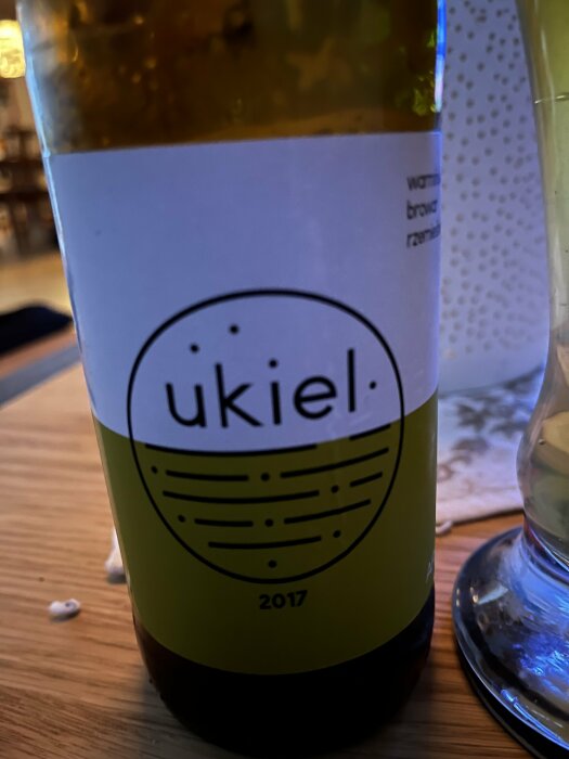 Flaska med etiketten 'ukiel' från Ukiel bryggeri, årgång 2017, på ett bord.