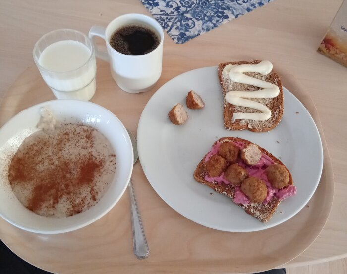 En frukost med havregrynsgröt, mackor med köttbullar och rödbetssallad, samt en kopp kaffe och ett glas mjölk.