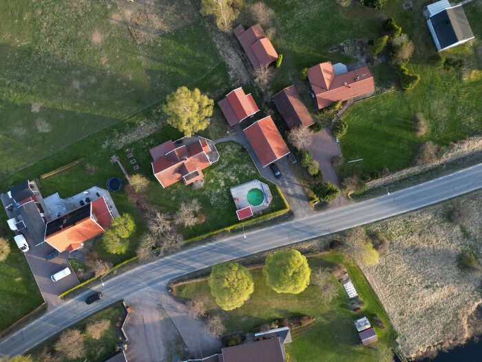 Flygbild på ett bostadsområde med tegelhus, trädgårdar och en korsning, sedd ovanifrån.