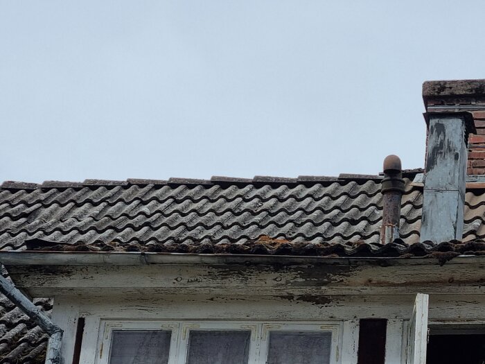 Slitet tak med betongpannor och ett gammalt ventilationsrör på en takkupa.