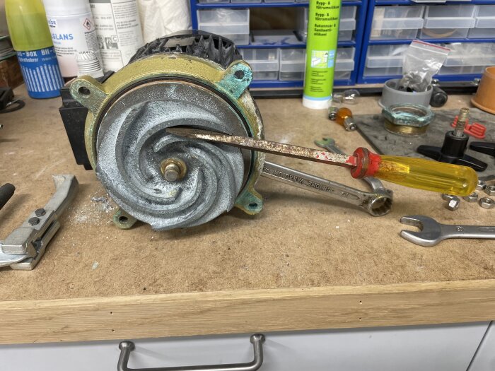 En öppnad elmotor på arbetsbänk med verktyg under lagerbyte, vid korrosionsskador.