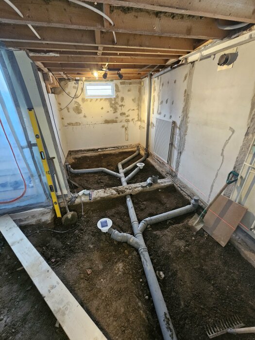 Pågående källarrenovering med utsatt VVS och jordgolv redo för isolering och golvvärme.