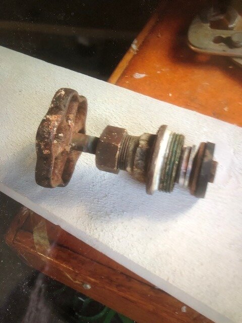 Rostig skivstång med viktskivor i olika storlekar på en vit arbetsbänk.