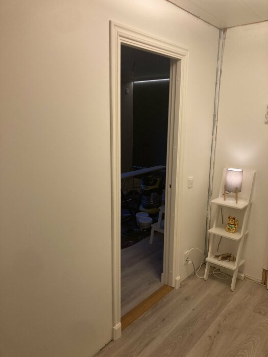 Nymonterad vit innerdörr i ett hem med ljusa laminatgolv och vit dörrfoder.