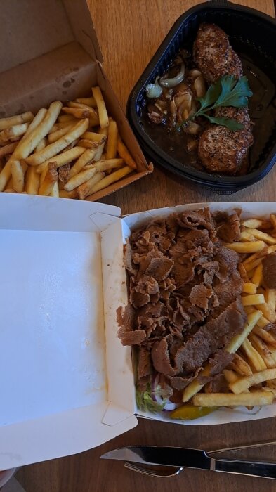 Kebabtallrik med pommes frites bredvid en biff med lök och pommes i take away-förpackningar.