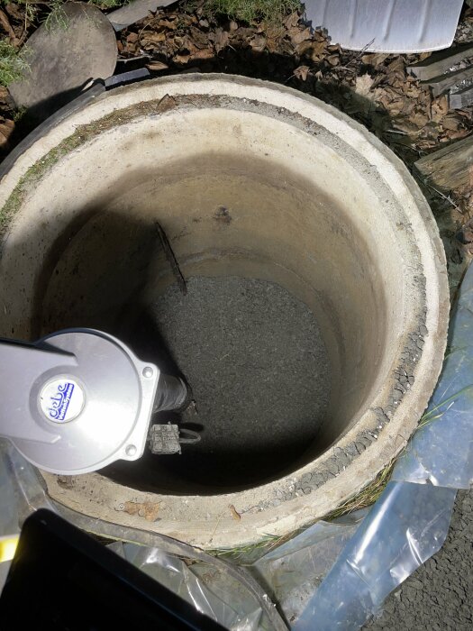 Ny vattenpump installerad i ett isolerat cementrör i borrhål för brunn.