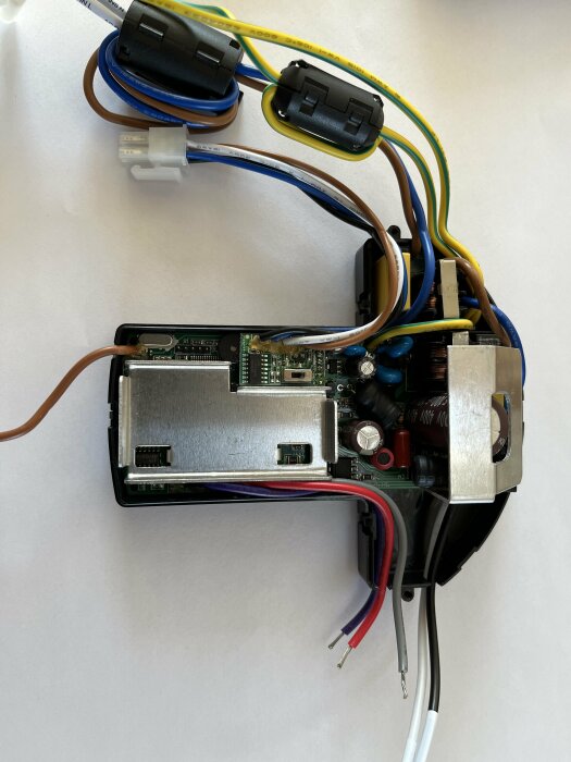 Öppen elektrisk dosa med synliga kablar och komponenter, inklusive ett kretskort och anslutningar.