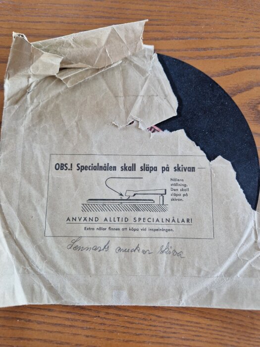 Sönderriven pappersficka för grammofonskiva med instruktioner för specialnål på svenska.