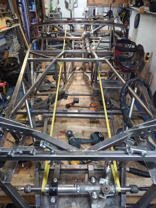 Styrväxeln monterad i en fordonstruktur med metallramar i ett verkstadsutrymme, verktyg och utrustning syns i bakgrunden.