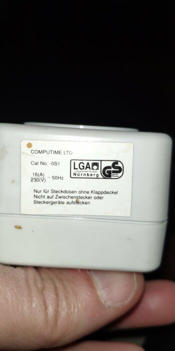 Närbild av en enhet med etikett som visar "COMPUTIME LTD" och säkerhetscertifieringar, hålls av en hand.