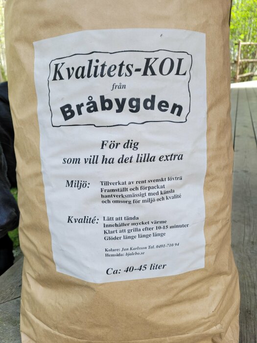 En säck med Kvalitets-KOL från Bräbygden med information om miljövänlighet och kvalitet, uppställd på en trädäck.