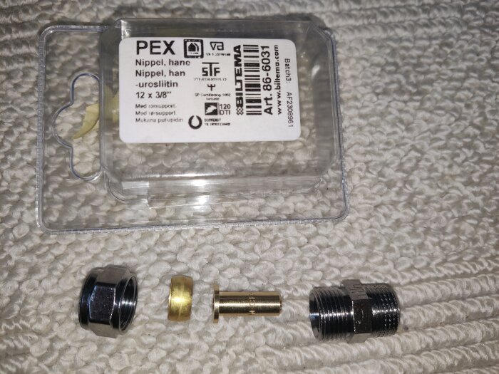 12mm PEX kopplingsset på ett tygförsett underlag inklusive förpackning och mässingsstödhylsa.