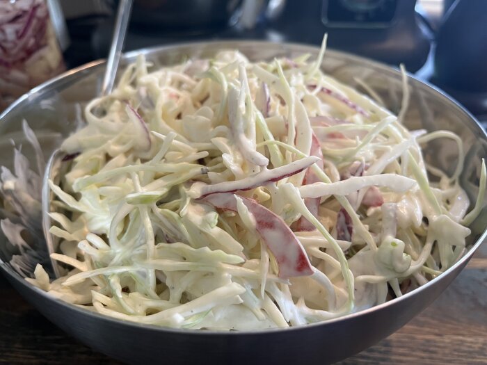 Skål med nyskuren coleslaw av vitkål och rödkål, redo att serveras.