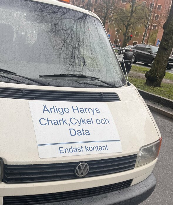 Vit skåpbil med skylt "Ärlige Harrys Chark, Cykel och Data Endast kontant" på framsidan.