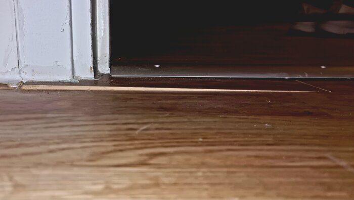 Skillnaden i golvnivå vid dörrkarmen, indikerar behov av justering eller reparation.