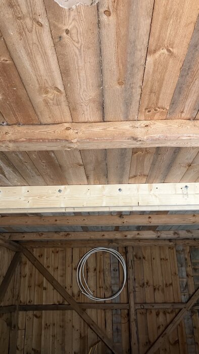 Träbjälkar och bärlinor i takkonstruktion med synliga snickeridetaljer i ett byggprojekt.
