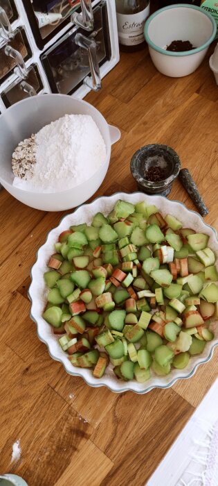 Rabarberpaj i tillagning med hackad rabarber i pajform och ingredienser redo på köksbänk.