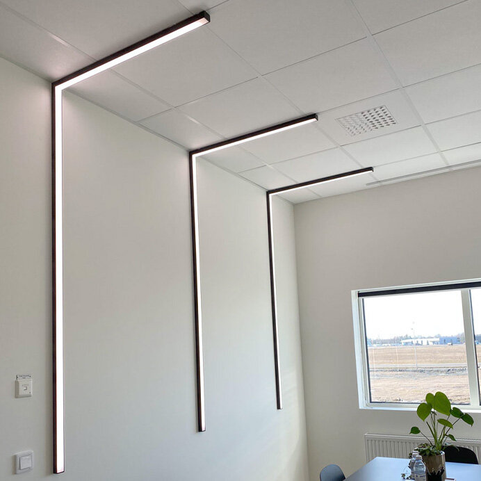LED-lister i L-form monterade i taket i ett modernt kontorsrum.
