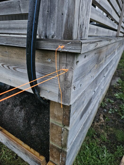 Hörn av en träkonstruktion med orange snöre markerande en planerad bärlinje, problem vid anslutning till balkskor.